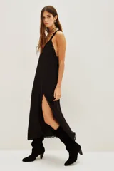 Vestido largo negro de viscosa con escote en V, tirantes finos, detalle de encaje en el escote y en la abertura lateral de la falda.