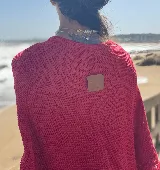 Poncho tejido en hilo de algodón, color rojo, con diseño de cuello redondo y terminaciones con flecos en el ruedo.