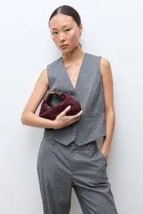 Chaleco sastrero de corte entallado con escote en V, cierre frontal con botones y bolsillos laterales simulados. Presenta un estampado de microcuadros en tonos grises.