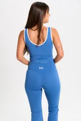 Conjunto deportivo de dos piezas color azul, compuesto por una musculosa con ribetes blancos y un pantalón de corte acampanado con cintura alta.