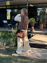 Chaleco tejido de punto en color chocolate, con cuello redondo y diseño sin mangas. Presenta un aplique frontal decorativo compuesto por tres figuras en forma de rombo en tonos tierra, bordeadas con hilo crudo.