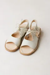 Sandalias de cuero color crudo, con tiras anchas sobre el empeine y ajuste con cordones finos.