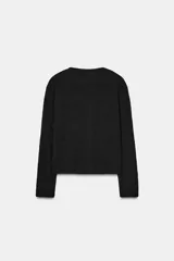 Chaqueta de punto texturizado color marrón oscuro, de corte cropped y cuello redondo. Presenta cierre frontal con botones dorados y dos bolsillos de plastrón decorativos con botón dorado en el pecho.