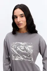 Remera de manga larga color beige, con cuello redondo y estampa gráfica frontal en color celeste.