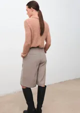 Polo de tejido de punto medio color marrón tostado, con diseño calado, manga larga y cuello con cierre de botones.
