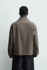 Sobrecamisa relaxed fit de Zara confeccionada en tejido negro con estructura diagonal. Presenta cuello subido, manga larga, bolsillos de vivo en la cadera y cierre frontal con cremallera.