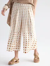 Pantalón palazzo color crudo con estampado de lunares marrones.