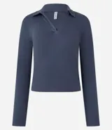 Blusa de manga larga confeccionada en tejido rib de algodón con elastano. Presenta un diseño ajustado al cuerpo con cuello polo y escote en V.