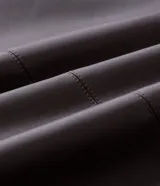 Pantalón de cuero sintético con corte barrel, de tiro alto y pierna ancha con estructura curva. Presenta bolsillos laterales tipo cuchillo y costuras decorativas con pespuntes visibles.