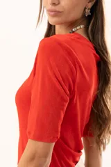 Remera de cuello redondo y manga corta, confeccionada en tejido elástico con un acabado suave y un leve brillo. Presenta un diseño básico con un pequeño isotipo bordado en la espalda.