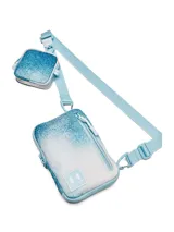 Bandolera Under Armour con diseño versátil convertible en riñonera o mochila de pecho. Presenta un estampado degradado en tonos celestes y blancos, con compartimento principal con cierre, bolsillo frontal con bloqueo RFID y un pequeño estuche extraíble para accesorios. Incluye correa ajustable y extraíble.
