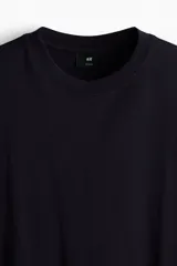 Remera de punto de algodón de peso medio en color negro, con cuello redondo ribeteado, hombros caídos, mangas cortas y corte relajado.
