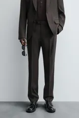 Pantalón de traje regular fit confeccionado en tejido de lana. Presenta bolsillos frontales, bolsillos traseros de vivo con botón y cierre frontal con cremallera y botón.
