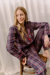 Pijama de franela de algodón con estampado de cuadros escoceses. Incluye camisa de manga larga con botones frontales y vivo a contraste, y pantalón recto con cintura elástica.