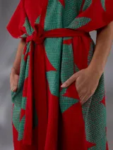 Capullo o kimono de paño 100% algodón, color rojo con estampado exclusivo en tono verde, de morfología amplia y envolvente, con bolsillos laterales y cinto independiente para ajustar la cintura.