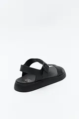 Sandalia baja negra con tiras anchas y hebilla lateral.