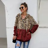 Campera tipo polar con cierre frontal, diseño combinado con estampado animal print en la parte superior y tejido de peluche blanco en la parte inferior. Cuenta con capucha con cordones ajustables y dos bolsillos frontales.