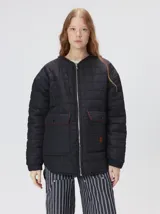 Campera reversible capitoneada con cierre frontal. Un lado es de color negro y el otro es de color beige, ambos con diseño acolchado. Cuenta con cuello redondo, mangas largas y bolsillos laterales.