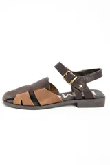 Sandalias cangrejeras de cuero tipo flats, con diseño bicolor en tonos marrón y tostado, tiras entrelazadas en el empeine y tira ajustable con hebilla en el talón.