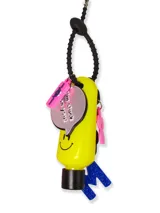 Llavero porta alcohol en gel con diseño de banana amarilla con cara sonriente. Incluye una correa de silicona negra, un dije metálico circular con frase grabada, un dije de silicona rosa y una letra M con glitter azul.