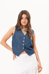Chaleco de denim fino y liviano azul, de silueta entallada con escote en V, cierre frontal de botones de nácar y diseño con terminación en puntas en la delantera.