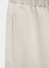 Pantalón de diseño balloon con cintura elástica, tiro medio y pinzas en el bajo. Presenta una textura ligeramente arrugada y forro interior.