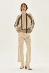 Polera de cuello alto confeccionada en lana lambswool, con diseño de bloques de color en tonos beige y marrón. Presenta mangas raglán con textura acanalada y detalles en hilo metalizado lurex.