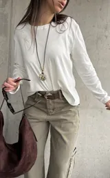 Remera blanca de manga larga con diseño holgado y escote bote. Cuenta con un delicado bordado floral en el hombro derecho.