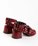 Sandalias de cuero color bordó con tres tiras horizontales sobre el empeine y pulsera al tobillo, ambas con apliques de tachas plateadas.