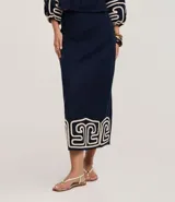 Pollera recta de largo midi en color azul marino, confeccionada en tejido de cambraia de algodón y lino. Presenta un bordado geométrico en color crema en el ruedo, cierre de cremallera y abertura central en la parte trasera.