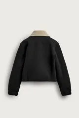 Cazadora boxy fit de tejido técnico negro con mezcla de algodón, de corte corto, manga larga con puños abotonados y cierre frontal con cremallera oculta. Cuenta con cuello solapa desmontable en tejido combinado color beige a contraste y bolsillos de vivo en la cadera.