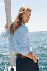 Chaqueta de punto en tono celeste, de cuello redondo, manga francesa y cierre frontal con botones dorados. Cuenta con bolsillos simulados con solapa y botones dorados en la parte delantera.