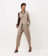 Pantalón carrot de viscolino color marrón, de corte amplio en la cadera y ajustado hacia los tobillos. Cuenta con cintura elástica en la parte posterior, lazo frontal para ajuste y caída liviana.