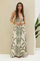 Vestido largo de diseño halter, color crudo con gran estampado de palmeras en tonos verdes y marrones.