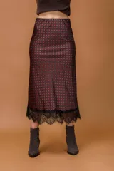 Falda midi de seda con estampado de lunares rojos sobre fondo oscuro, con detalle de encaje negro en el ruedo.