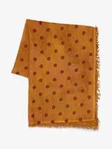 Bufanda rectangular color ocre con lunares marrones y flecos en los extremos.