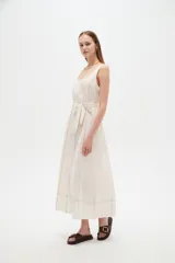 Vestido midi de lino color beige con diseño a cuadros discretos, cuello cuadrado, sin mangas y con cinturón ajustable en la cintura.