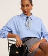Camisa celeste oversized de tricolina con cuello, abotonado delantero y mangas largas. Incluye pañuelo estampado para el cuello.
