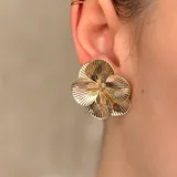 Par de aros tipo caravanas con diseño de flor de cuatro pétalos con textura estriada en acabado plateado.