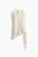Vestido corto de lunares color blanco, con tiras finas cruzadas en la espalda, escote con volados y bajo asimétrico con detalles de volados largos.