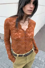 Top de manga larga color marrón óxido, confeccionado en tejido de encaje floral. Presenta escote en V con cierre frontal de botones pequeños.