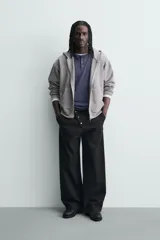 Pantalón wide fit de algodón con efecto lavado, corte recto y holgado. Presenta un cierre frontal cruzado con botones y un alamar metálico distintivo, además de bolsillos frontales y traseros de plastrón.