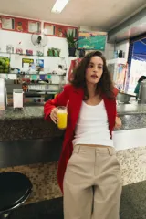 Abrigo largo de Zara confeccionado en mezcla de lana color rojo, con cuello de solapa, manga larga, bolsillos con solapa en el frente y cierre frontal de botones negros.
