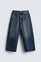 Jeans de denim de algodón, color azul oscuro con efecto lavado. Presentan un corte muy holgado (baggy fit) en toda la pierna y tiro medio. Tienen cinco bolsillos y cierre frontal con cremallera y botón.