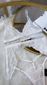 Set de lencería de cuatro piezas compuesto por bralette de encaje y microtul, tanga regulable, portaligas y ligas. Diseño con transparencias y detalles de encaje.