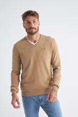 Sweater de tejido de punto color beige, con escote en V, mangas largas y puños y dobladillo acanalados. Presenta un pequeño logo bordado en el pecho.