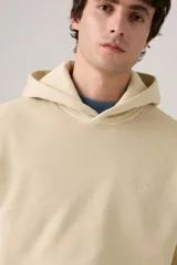 Buzo hoodie color crema con logo bordado en el pecho y bolsillo tipo canguro.