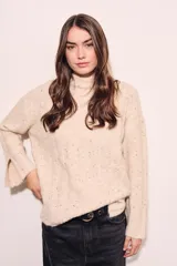 Sweater color crema con cuello alto, tejido de punto con textura y mangas largas con puños acampanados.