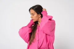 Camisa oversize color fucsia, de lino, con cuello camisero, cierre frontal con botones y mangas largas abullonadas con puños elásticos.