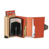 Billetera compacta Baleine de la colección Double Alabama, fabricada en cuero sintético color beige con detalles en naranja. Cuenta con doble compartimento de aluminio con sistema deslizante para tarjetas y protección RFID.